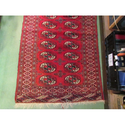 4221 - A Middle-Eastern red ground rug with two rows of lozenges and multiple borders, tasselled ends, 160c... 