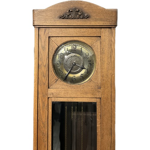 7098 - A 1920s oak long case clock with brass Arabic dial, bevelled glazing, with pendulum and weights