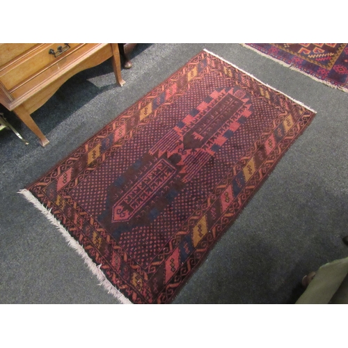 1065 - Two red ground rugs with tasselled ends, 137cm x 84cm and 127cm x 78cm