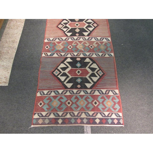 1102 - A red ground Kilim rug with geometric motifs, 300cm x 102cm