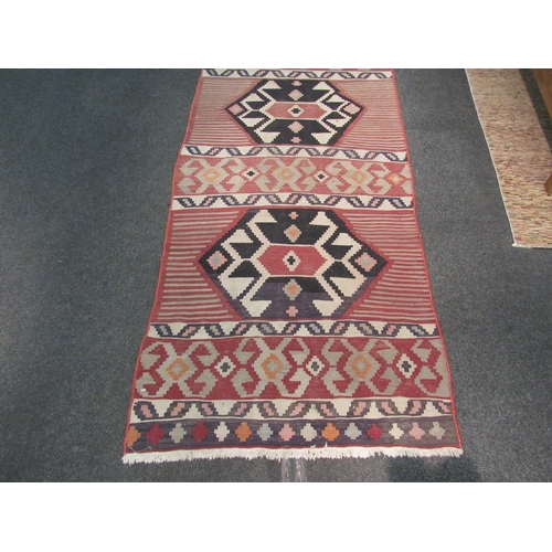 1102 - A red ground Kilim rug with geometric motifs, 300cm x 102cm