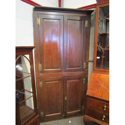 1050 - A Georgian country oak panelled four door full height corner cupboard having brass 