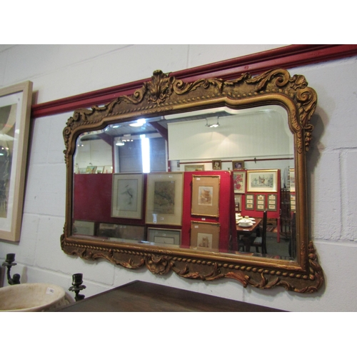 1051 - An ornate gilt framed wall mirror with bevelled edge, 66cm x 90cm wide total