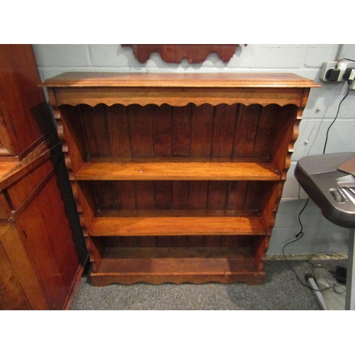 1065 - An oak three tier half height bookcase with wavy frieze, 110cm high x 101cm wide x 23cm deep