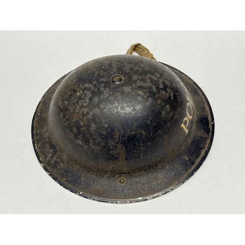 9260 - A WWII helmet painted for police use, dark blue with POLICE lettering, with liner and chinstrap, cor... 