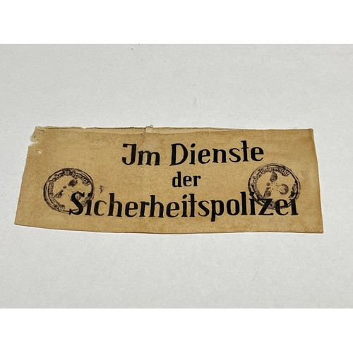 9457 - An armband bearing the lettering ‘Im Dienste der Sicherheitspolizei’ (In the service of the security... 