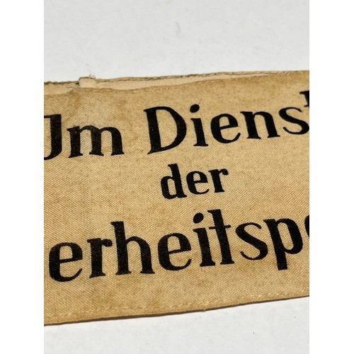 9457 - An armband bearing the lettering ‘Im Dienste der Sicherheitspolizei’ (In the service of the security... 