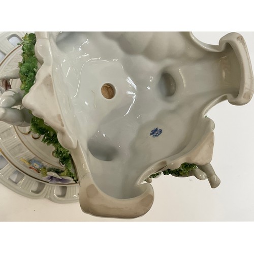 6161 - A 20th Century Dresden centre bowl held aloft by cherubs reading and playing musical instruments on ... 