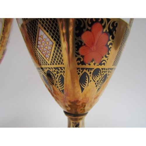 6223 - A pair of Royal Crown Derby Imari pattern urns, ovoid form with fixed knop cover and two high loop h... 