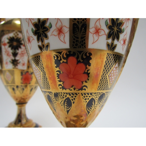 6223 - A pair of Royal Crown Derby Imari pattern urns, ovoid form with fixed knop cover and two high loop h... 