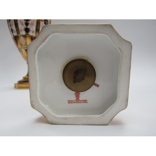 6223 - A pair of Royal Crown Derby Imari pattern urns, ovoid form with fixed knop cover and two high loop h... 