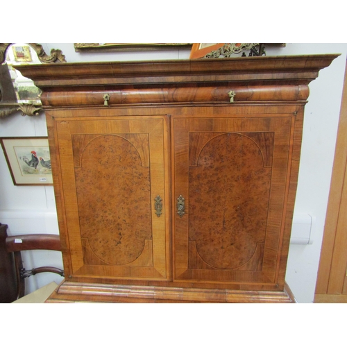 6067 - A William & Mary burr walnut veneered cabinet on chest, ogee pediment over single top drawer. The do... 