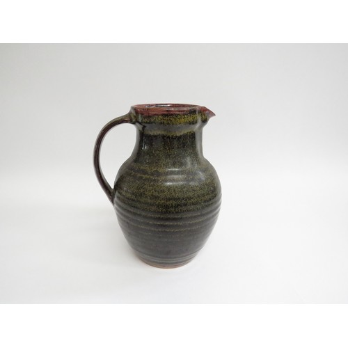 9087 - A Winchcombe Pottery tenmoku glazed stoneware jug. Impressed pottery seal. 21cm high