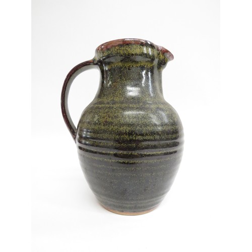 9087 - A Winchcombe Pottery tenmoku glazed stoneware jug. Impressed pottery seal. 21cm high