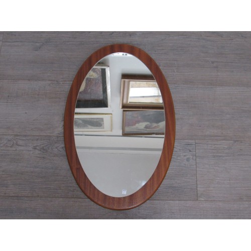 9311 - A Mid Century teak backed oval wall mirror. Overall size 57cm x 36cm