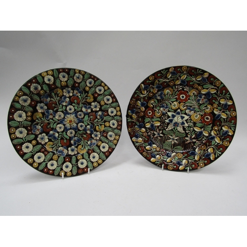 6103 - A pair of Continental glazed and painted clay wall plates, 26.5cm diameter