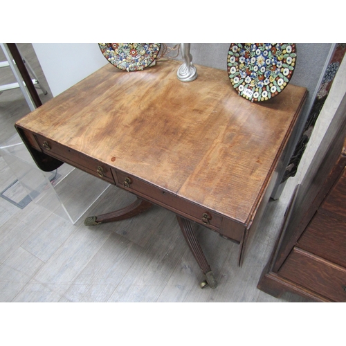 6106 - A Regency mahogany sofa table with two drawers turned stem to quatraform base, reeded legs to cup ca... 