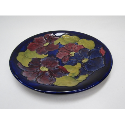 6118 - A Moorcroft Clematis pattern plate on blue ground, 26cm diameter