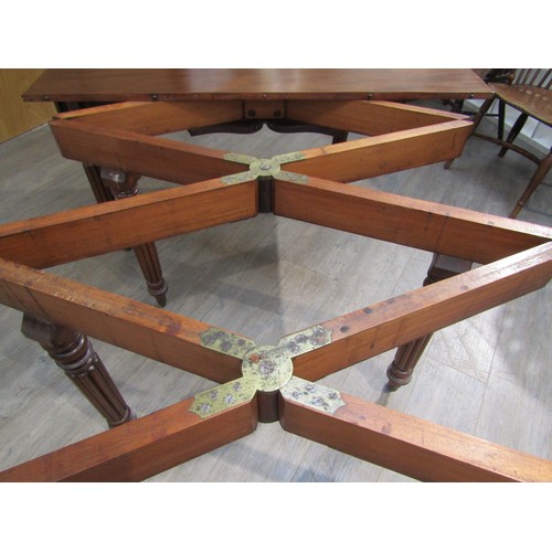 6197 - A Georgian mahogany concertina action extending dining table of rounded square form raised upon six ... 