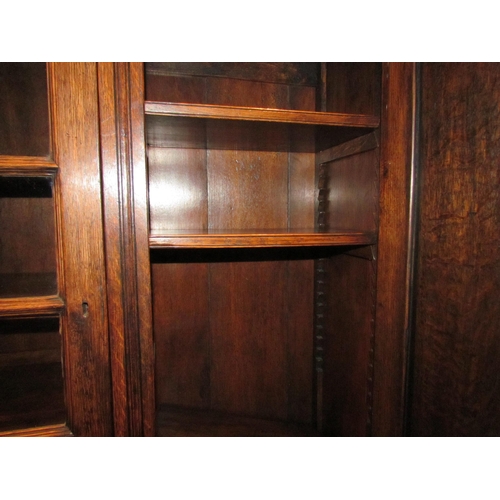 1094 - A carved and pegged oak three door bookcase with two keys over stile feet, 98cm high x 141cm wide x ... 