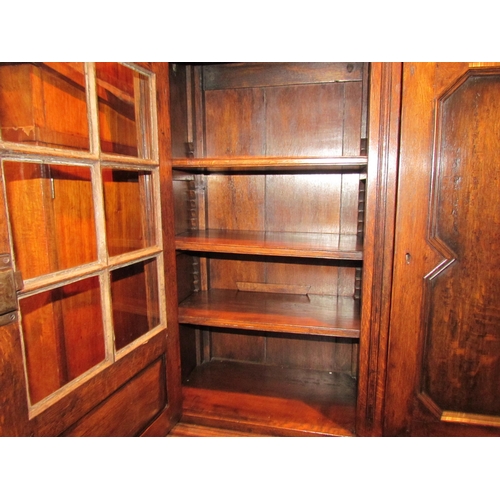 1094 - A carved and pegged oak three door bookcase with two keys over stile feet, 98cm high x 141cm wide x ... 