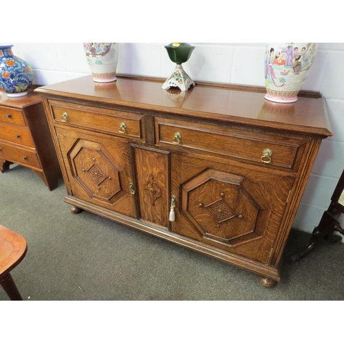 1011 - An early 20th Century oak sideboard, the two drawers over twin geometric moulded doors, on squashed ... 