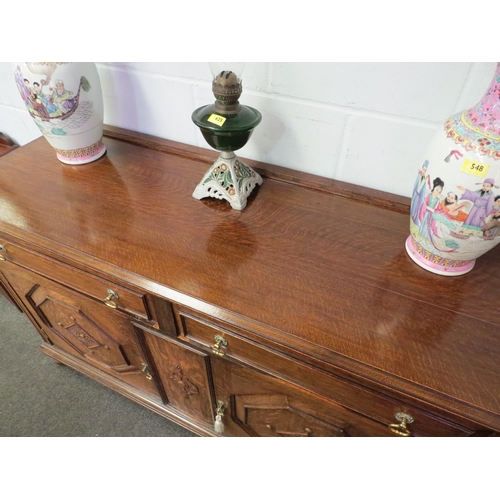 1011 - An early 20th Century oak sideboard, the two drawers over twin geometric moulded doors, on squashed ... 