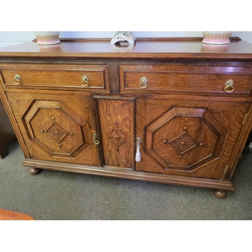 1011 - An early 20th Century oak sideboard, the two drawers over twin geometric moulded doors, on squashed ... 