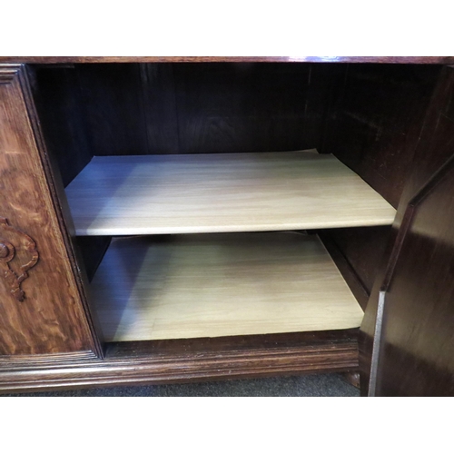 1011 - An early 20th Century oak sideboard, the two drawers over twin geometric moulded doors, on squashed ... 