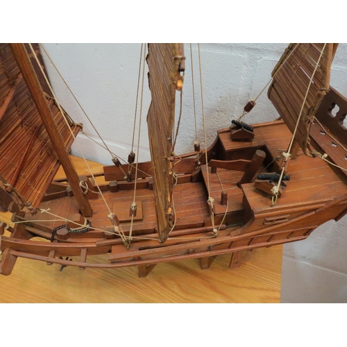 1043 - An Eastern mid-20th Century handbuilt model ship on stand fitted with sails and cannons, brought bac... 