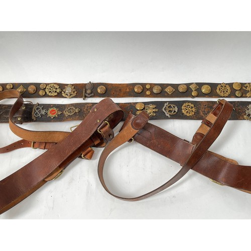 9078 - Two Sam Browne leather belts together with two further belts with applied military badges including ... 