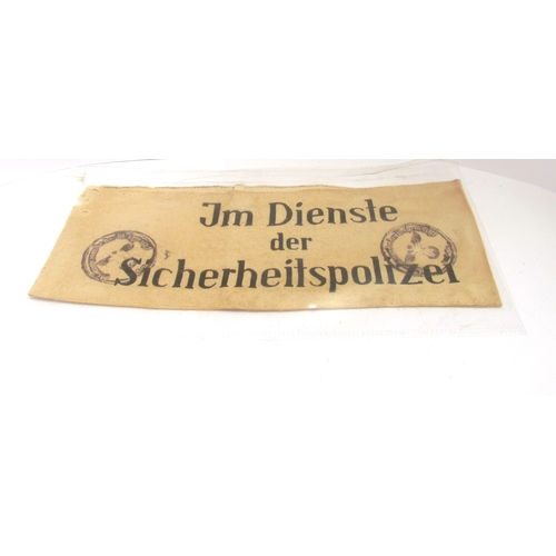 9457 - An armband bearing the lettering ‘Im Dienste der Sicherheitspolizei’ (In the service of the security... 