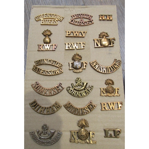 9438 - A collection of British Regimental insignia, mainly brass shoulder titles including Somerset and Cor... 