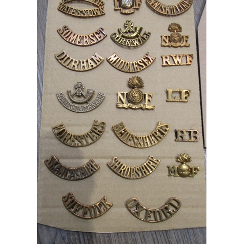 9438 - A collection of British Regimental insignia, mainly brass shoulder titles including Somerset and Cor... 