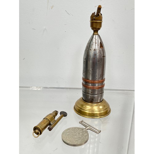 9520 - A trench art table lighter crafted from a shell head, together with a pocket lighter stamped R.K., a... 