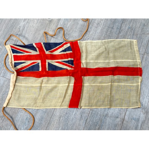 9522 - A vintage British White Ensign flag, 82cm x 44.5cm, together with a 1940 dated Brodie helmet shell a... 