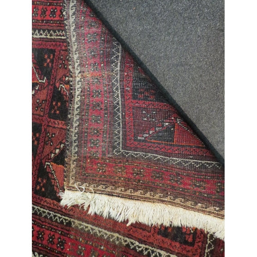 1048 - An Eastern red ground geometric design rug with tasselled ends, 153cm x 82cm