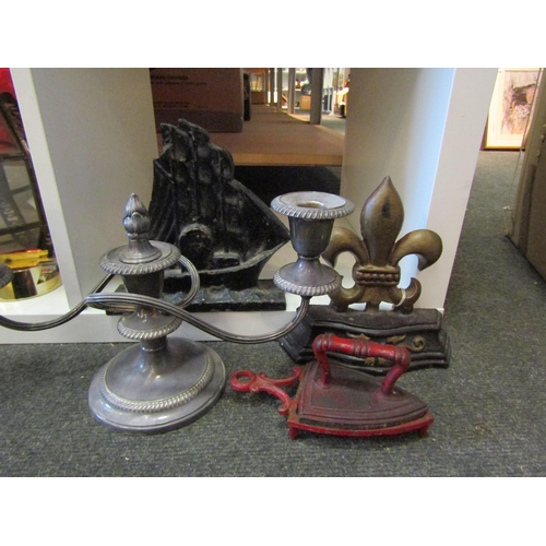 1608 - A twin branch candlestick, two cast metal door stops and a miniature iron on trivet (4)            G... 