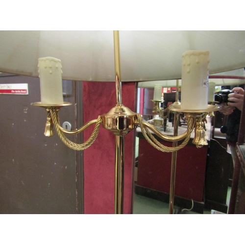 4144 - A brass electric standard lamp with swags and tails decoration the twin scones over a tripod base