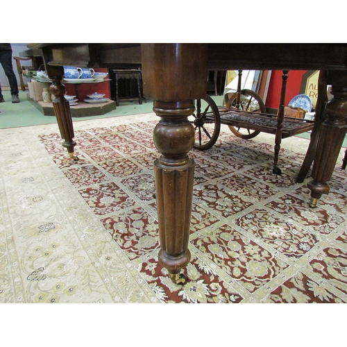 4174 - A mid-Victorian mahogany extending dining table with turned fluted legs on brass and porcelain casto... 