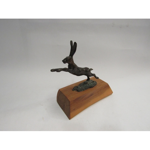 4319 - A bronze leaping hare figure on wood plinth base, (plinth 17cm long)