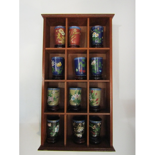 4443 - A set of 12 Japanese cloisonne pots within a display shelf, various designs incuding floral sprays