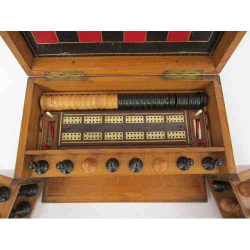 9056 - An early 20th Century oak cased games compendium with boxwood and ebony chess pieces (king 2.5” high... 