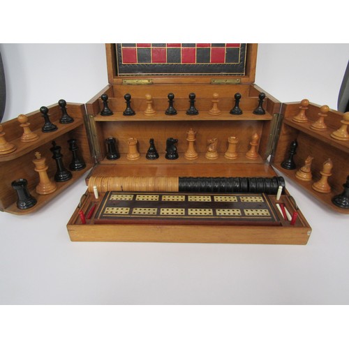 9056 - An early 20th Century oak cased games compendium with boxwood and ebony chess pieces (king 2.5” high... 