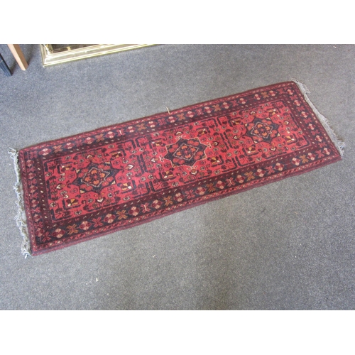 1017 - A small Eastern red ground wool runner rug, 150cm x 52cm