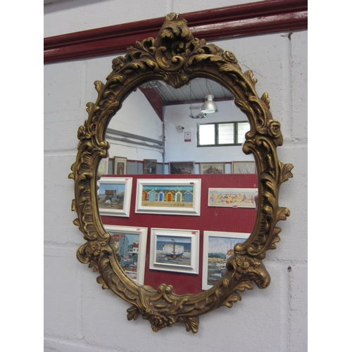1024 - A gilt gesso Rococo style wall mirror with scrolled gilt foliate frame, 60cm height     (E) £15-20