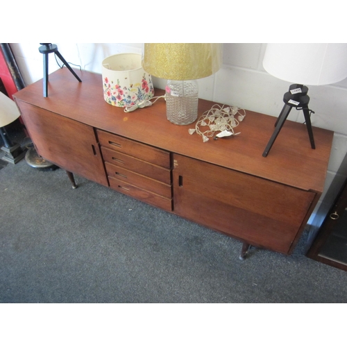 1063 - A retro teak sideboard, central bank of four drawers flanked by two cupboards, veneer damaged to doo... 