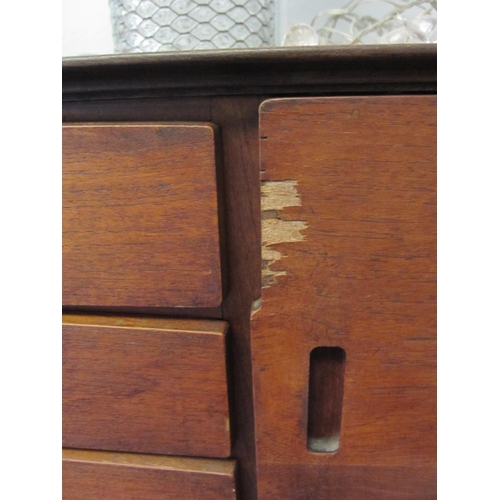 1063 - A retro teak sideboard, central bank of four drawers flanked by two cupboards, veneer damaged to doo... 