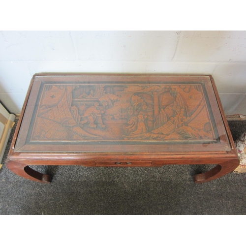 1075 - A 20th Century camphor wood coffee table with deeply carved top depicting Oriental figural landscape... 