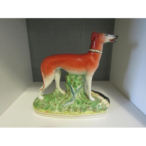 1245 - A Staffordshire hunting hound standing over a hare a/f repair to left ear, 18cm height